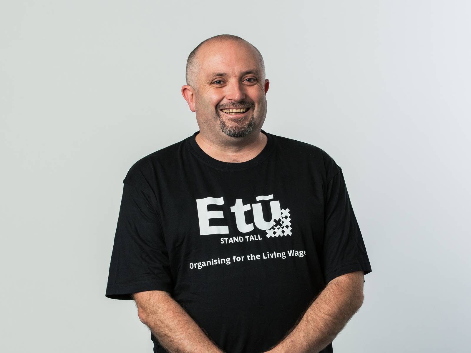 John in an 'E tū - Organising for the Living Wage' t-shirt