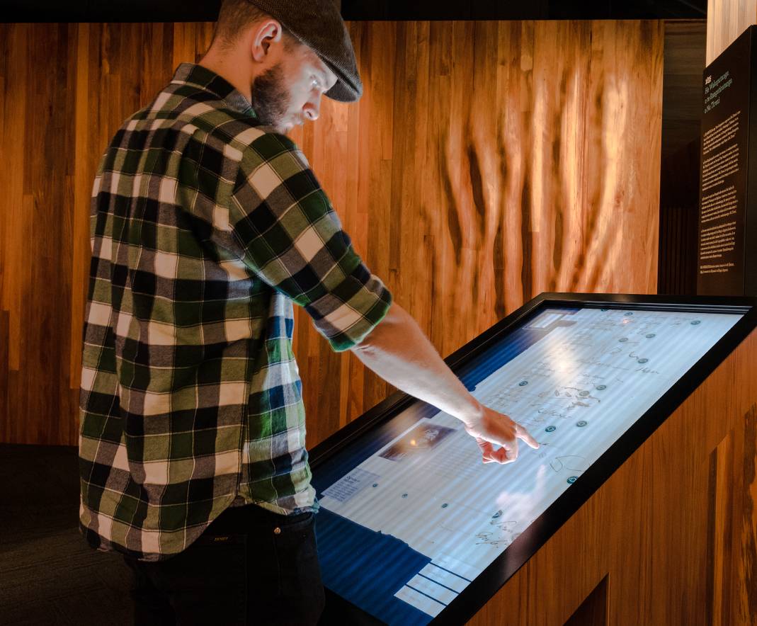 Someone using a touchscreen at the He Tohu exhibition